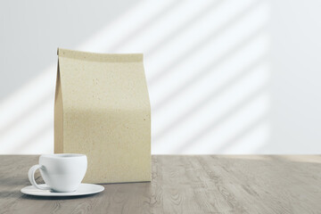 Fototapeta na wymiar Blank craft paper tea package with white coffee mug on wooden table with light background. Mock up