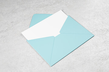 Blue color envelope with blank white postal card on concrete table. Mockup