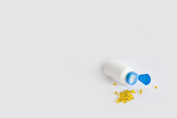 Yellow oil capsules with vitamin D, omega poured from a plastic white bottle. Healthy diet concept