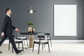 Blank white poster on black wall in modern dining room with round table, black wooden chairs around and businessman