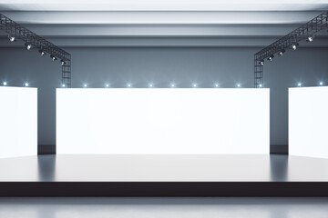 Blank white glowing boards in spacious hall with black glossy stage in the center and concrete...