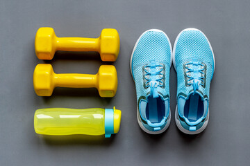 Top view of fitness accessories with dumbbells and sneakers