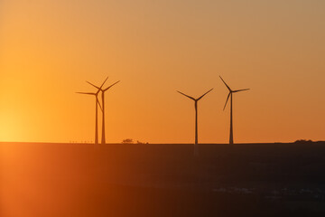 Eoliennes à axe horizontal éclairées par un lever de soleil rougeoyant au matin