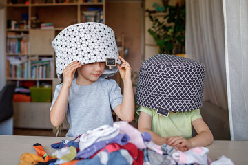 Household chores for children. Kids cleaning their room, sorting dry socks and arranging them into personal baskets with fun, they turn cleaning into the game. Everyday routine, lifestyle