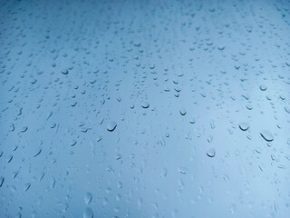 Raindrops on a window pane close-up. Abstract blue background.