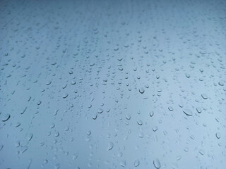 Raindrops on a window pane close-up. Abstract blue background.