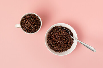 White mug and cup with spoon with coffee roasted beans on pink surface. Flat lay.