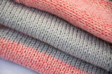 Knitted sweater. Knitted fabric. Knitted texture of loops. Pink jersey with gray stripes.