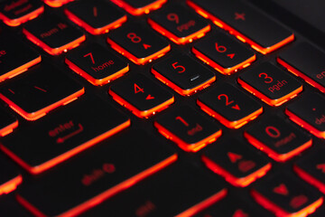Black gaming keyboard with red backlight. Closeup focused on numeric keys.