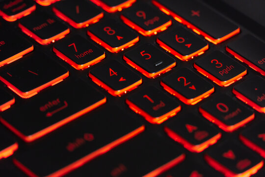 Black gaming keyboard with red backlight. Closeup focused on numeric keys.