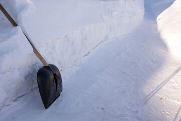 Shovel in the snow. Raking away the snow in the garden. High snowdrifts. There is a lot of snow in the garden in winter.
