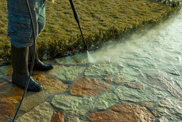 Worker with pressure washer cleaning street