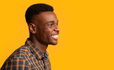 Side view shot of joyful millennial african guy isolated over yellow background .