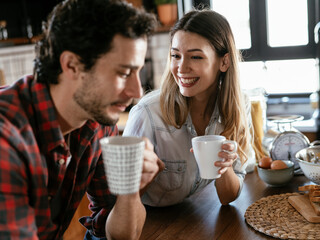  Loving couple drinking coffe in the kitchen. Happy smiling woman enjoy in the morning with her boyfriend.