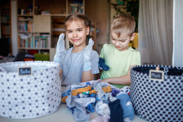 Household chores for children. Kids cleaning their room, sorting dry socks and arranging them into...