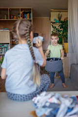 Household chores for children. Kids cleaning their room, sorting dry socks and arranging them into personal baskets with fun, they turn cleaning into the game. Everyday routine, lifestyle