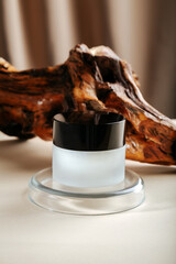 Skincare Cream in transparent round jar on color beige background on petri dish laboratory glassware podium pedestal platform. Skin care cosmetics mock up product photography. Natural eco wood