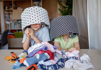 Household chores for children. Kids cleaning their room, sorting dry socks and arranging them into personal baskets with fun, they turn cleaning into the game. Everyday routine, lifestyle