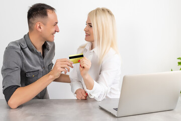 Excited young couple shopping online, holding credit card and looking