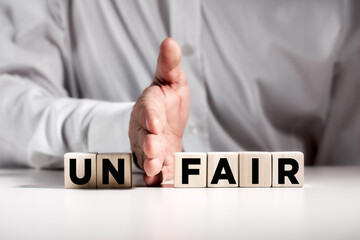 Businessman hand puts away the first two letters from the word unfair and transforms it into fair....
