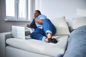 Fototapeta na wymiar Tranquil African American woman enjoying her rest on sofa