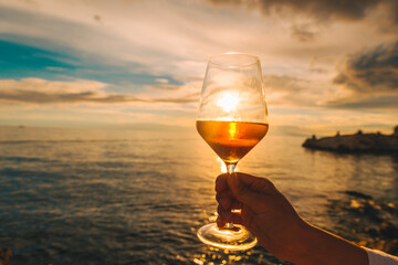 woman hand holding wine glass on sunset