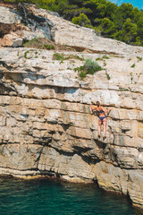 sporty strong woman climber at rock hill at sea beach