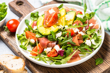 Green salad with avocado, salad leaves, jamon and tomatoes. Healthy diet lunch. Cloth up.