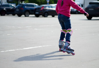 A teenage girl is rollerblading on the playground. View of the child from the back, without a face. Blurred focus, copying text