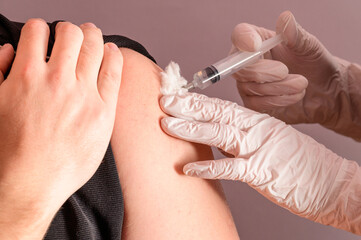 Vaccination close up, injection of vaccine in hand, doctor in white gloves.