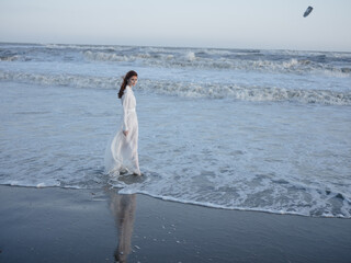 Woman in white dress on the beach by the ocean