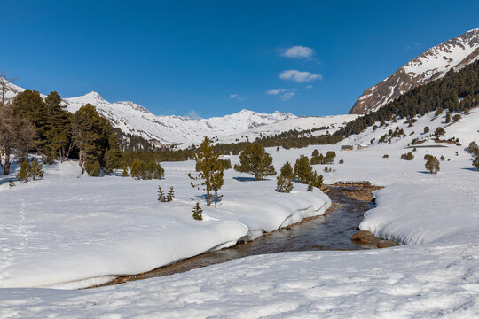 Panorama with lots of snow on Lukmanier in Ticino, on the Swiss Alps and a romantic stream through the landscape