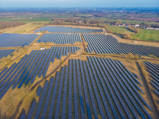 Aerial drone shot of rows of solar panels in green countryside landscape