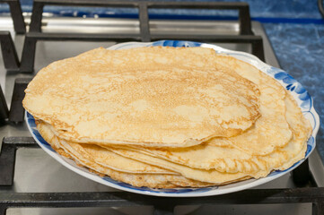 Maslenitsa holiday. Cooked pancakes in a plate are on the stove.