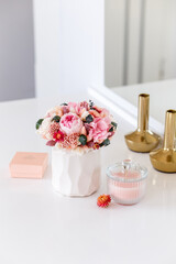 Bouquet with roses, peony, spikelets and dry flowers in pink colors. Stabilized flowers in a white ceramic vase at home on the dressing table. Interior decor.