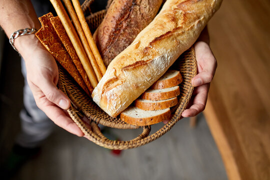Close yp of man hand, holding basket with various bread freshly baked.