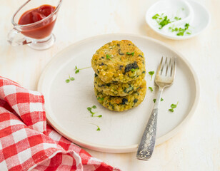 Fried burgers or cutlets of bulgur, carrots and spinach on a light ceramic plate on a light concrete background. Bulgur recipes.