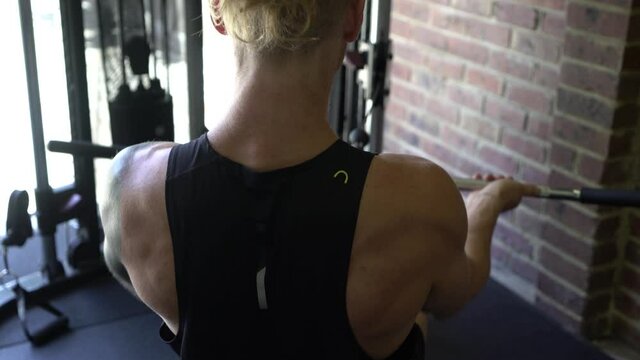 Tattoo man muscles in home gym rowing shot from behind