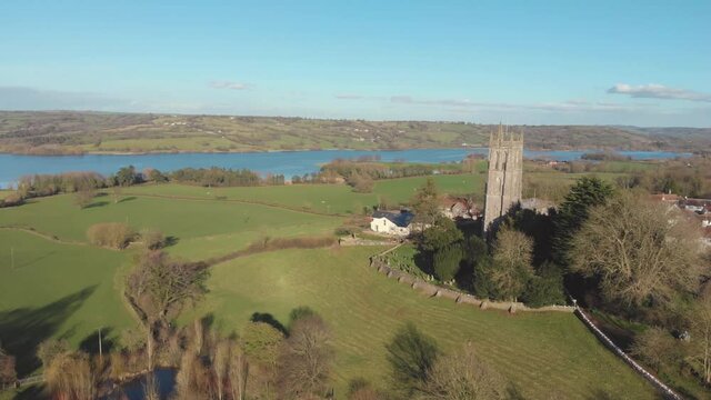 Aerial drone view of ancient 15th century church and lake in Blagdon, Somerset, England