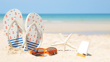 Summer accessories. Planing to travel with sunblock and sandal on the beautiful beach and blue sky background. Tropical fashion. Summer Fashion on holiday concept.