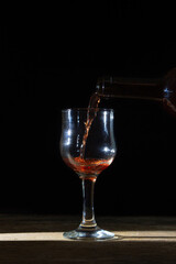 Homemade red wine is poured into a glass on a dark background. Glass of red wine on a black background. Alcoholic beverage