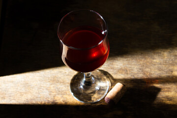 Glass of red homemade wine on a wooden surface. Glass of red wine on a dark background. Alcoholic beverage