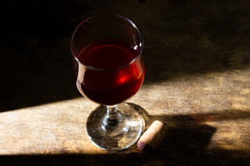 Glass of red homemade wine on a wooden surface. Glass of red wine on a dark background. Alcoholic beverage
