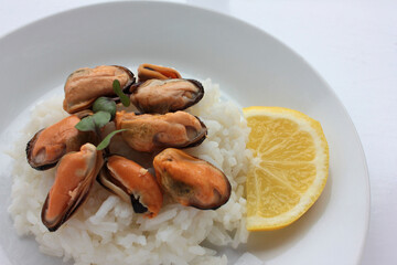 Dish with mussel risotto on white background. Top view of white rice with seafood and lemon slice. Copy space. Healthy eating concept
