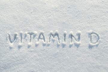 Inscription vitamin D on clean snow, in the bright rays of the winter sun. Health concept. Copy...