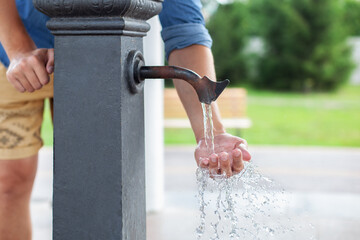 Man washing his hand in faucet water. Сity water tap with drinkable water in park. Drinking...