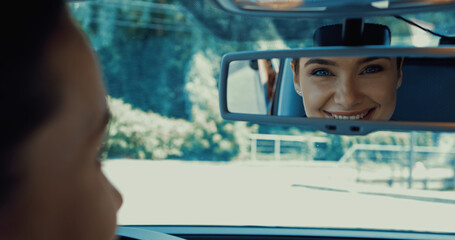 blurred and happy woman smiling while looking in rearview mirror