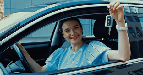 cheerful young woman holding key from new car