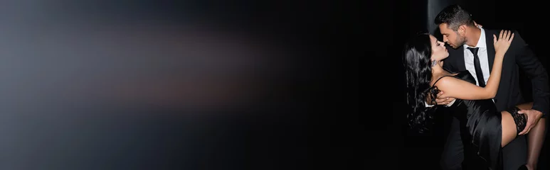 Man in formal wear kissing brunette woman on black background, banner © LIGHTFIELD STUDIOS