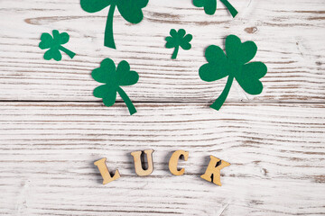 Word luck and shamrock clover leaves on a white wooden background. Happy St. Patrick's Day. Irish...